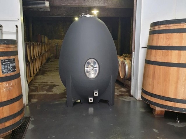 cuve à vin ovoïde à côté de deux cuves en bois